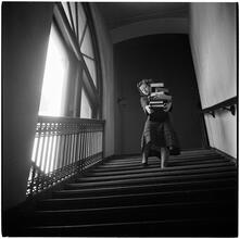 Columbia University [Student carrying books down a flight of stairs.]