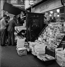Newsstand [People browsing through magazine racks at a busy sidewalk newsstand.]