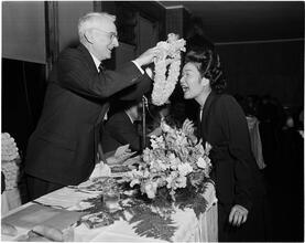 Dale Carnegie [Dale Carnegie presents a lei to one of his pupils, Mrs. Ethel de Saussure of Hawaii.]
