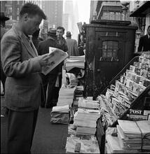 Newsstand [People browsing through magazine racks at a busy sidewalk newsstand.]