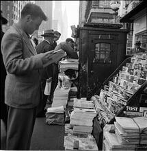 Newsstand [People browsing through magazine racks at a busy sidewalk newsstand.]