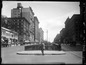 Broadway Series. Looking north from 111th Street. Two people in foreground. Four tall buildings at left center. Building with 3 balconies is at corner of 112th Street.