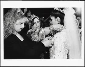 [Women pinning gold coins to bride's dress at a Palestinian wedding at Widdi's Catering Hall.]